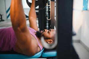 Weight lifter at the bench press lifting a barbell on an bench. photo