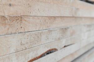 Stack of lumber of a wooden board from a tree, close-up, background. Wooden boards at the sawmill, carpentry workshop. Sawing and air drying of wood. Woodworking industry. Wooden boards photo