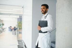 Portrait of confident Asian Indian medical doctor standing at hospital building photo