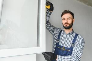 Worker installing plastic window indoors photo