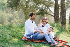 happy young family spending time outdoor on a summer day have fun at beautiful park in nature while sitting on the green grass. Happy family. photo