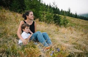 joven mamá con bebé chico de viaje. madre en excursionismo aventuras con niño, familia viaje en montañas. nacional parque. caminata con niños. activo verano vacaciones. foto