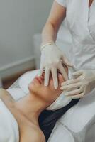 girl at a cosmetologist's office doing skin cleansing photo