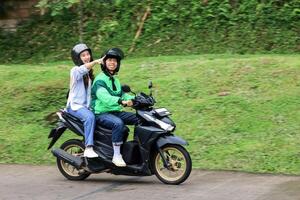 asiático en línea Taxi motocicleta pasajero señalando un sitio con sonrisa foto