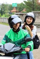 Female Passenger SMiling to the Ojek Driver Online, Showing Direction photo