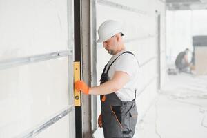 Man holding level against plasterboard, interior drywall. Attic renovation photo