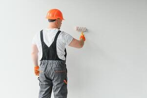 Painter using a paint roller and painting a wall isolated on white background. photo