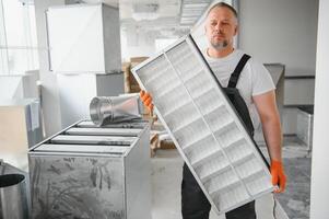 trabajador participación aire filtrar para instalando en el oficina ventilación sistema. pureza de el aire concepto. foto