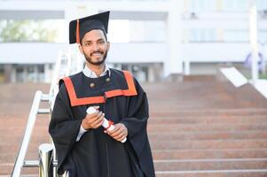 hermoso indio graduado en graduación resplandor con diploma. foto