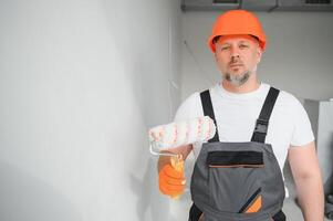 hombre estar en el habitación con pintar rodillo en su mano foto