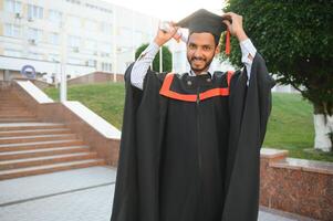 Portrait of indian handsome male graduate in graduation robe. photo