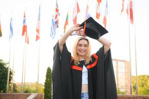 Happy university graduate girl. The girl is standing near the university against the background of the flags of different countries. The concept of international education. photo