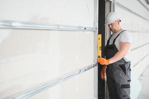 Man holding level against plasterboard, interior drywall. Attic renovation photo