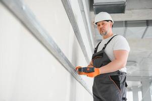 man drywall worker installing plasterboard sheet to wall photo