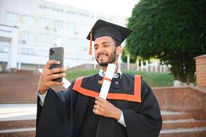 Handsome indian graduate in graduation glow with diploma. photo