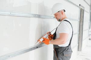 The builder fills the seam between plasterboard plates a silicone gun photo