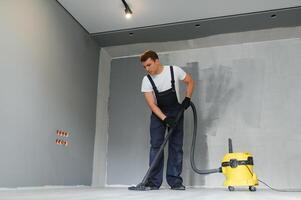 A worker vacuums a room after repairing the floors. Apartment after renovation with a vacuum cleaner. photo