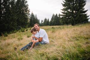 contento padre y pequeño niño son caminando en el montañas. del padre día. vacaciones en el nacional parque foto