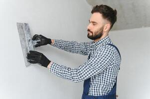 Man removes holes and bumps on the wall with a spatula and plaster photo