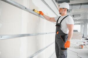 man drywall worker installing plasterboard sheet to wall photo