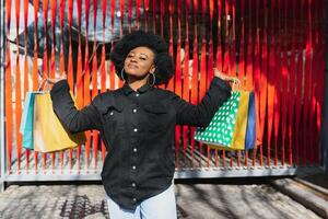 Attractive young African-American woman shopping - shopping bags, outdoors, street view, suitable for holiday shopping themes, among others photo