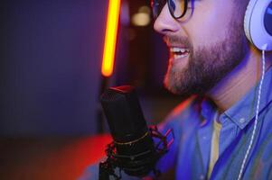 Young man recording or streaming podcast using microphone at his small broadcast studio. Content creator. photo