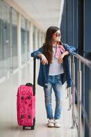 stylish little girl with a suitcase at the airport flying to rest on vacation photo
