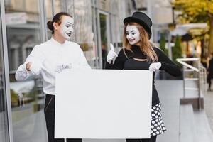 Your text here. Actors mimes holding empty white letter. Colorful portrait with gray background. April fools day photo