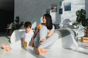 Beautiful woman with her son drinking juice in the morning in bed. Healthy eating concept photo