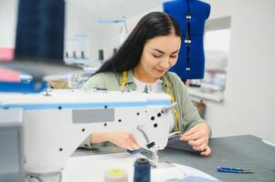 Young woman working as seamstress in clothing factory. photo