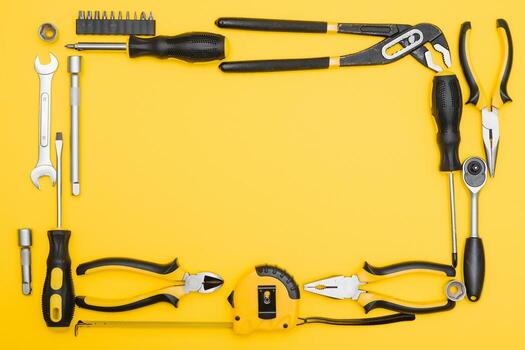 Tools top view on yellow background. Plier, open wrenches, screwdrivers and staple gun flat lay with copy space photo