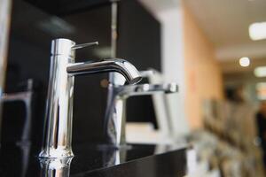 Rows of new faucets in plumbing shop, closeup photo