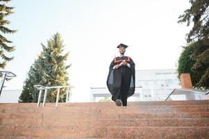 Handsome indian graduate in graduation glow with diploma. photo