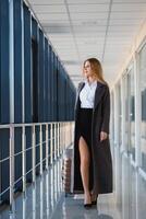 Stylish businesswoman with luggage at the airport.. Attractive lady with travel suitcase walking along airport waiting room stock photo