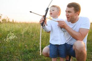 un padre enseñando su hijo cómo a disparar arco. foto