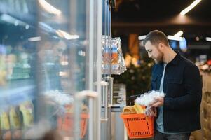 Portrait of smiling man walking with his trolley on aisle at supermarket. photo