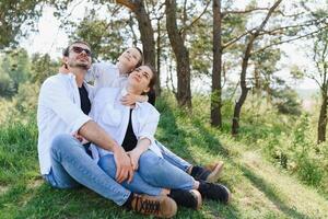 happy young family spending time outdoor on a summer day have fun at beautiful park in nature while sitting on the green grass. Happy family. photo