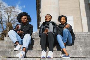 elegante africano americano muchachas Bebiendo café en el calle foto