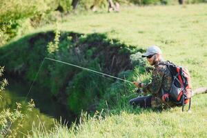 young fisherman fishes near the river. The concept of outdoor activities and fishing photo