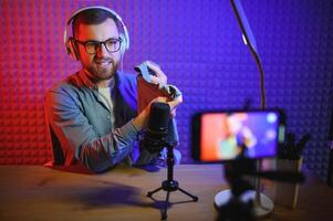 Joyful young man recording unboxing video in studio photo