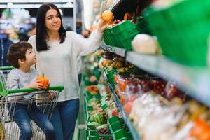 woman and child boy during family shopping with trolley at supermarket photo