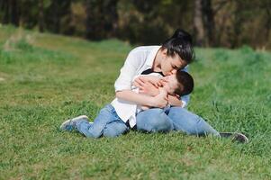 Happy family Mother with son child playing having fun together on the grass in sunny summer day, life moment photo