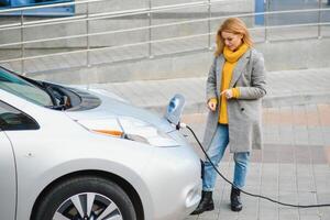 Woman charging electro car at the electric gas station. photo