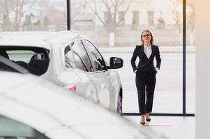 auto business, car sale, consumerism and people concept - happy woman taking car key from dealer in auto show or salon. photo