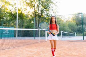 Cute little girl playing badminton outdoors on warm and sunny summer day photo