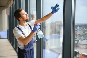 un empleado de un profesional limpieza Servicio lavados el vaso de el ventanas de el edificio. escaparate limpieza para tiendas y negocios foto