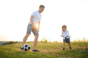 joven padre con su pequeño hijo jugando fútbol, del padre día. foto