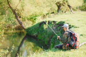 young fisherman fishes near the river. The concept of outdoor activities and fishing photo