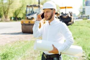 engineer near road machinery. The concept of building a new asphalt road. Road repair. Road service worker near the rink. photo