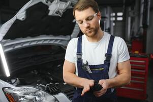 Auto mechanic working on car engine in mechanics garage. Repair service. photo